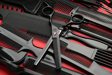 Photo of Different hairdresser's tools on red background, closeup