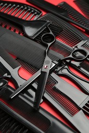 Photo of Different hairdresser's tools on red background, closeup