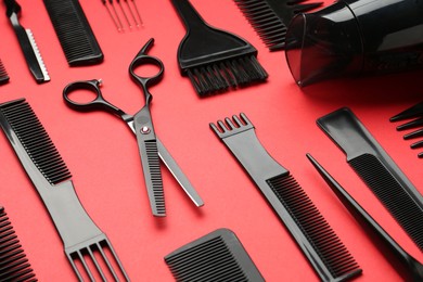 Photo of Different hairdresser's tools on red background, closeup