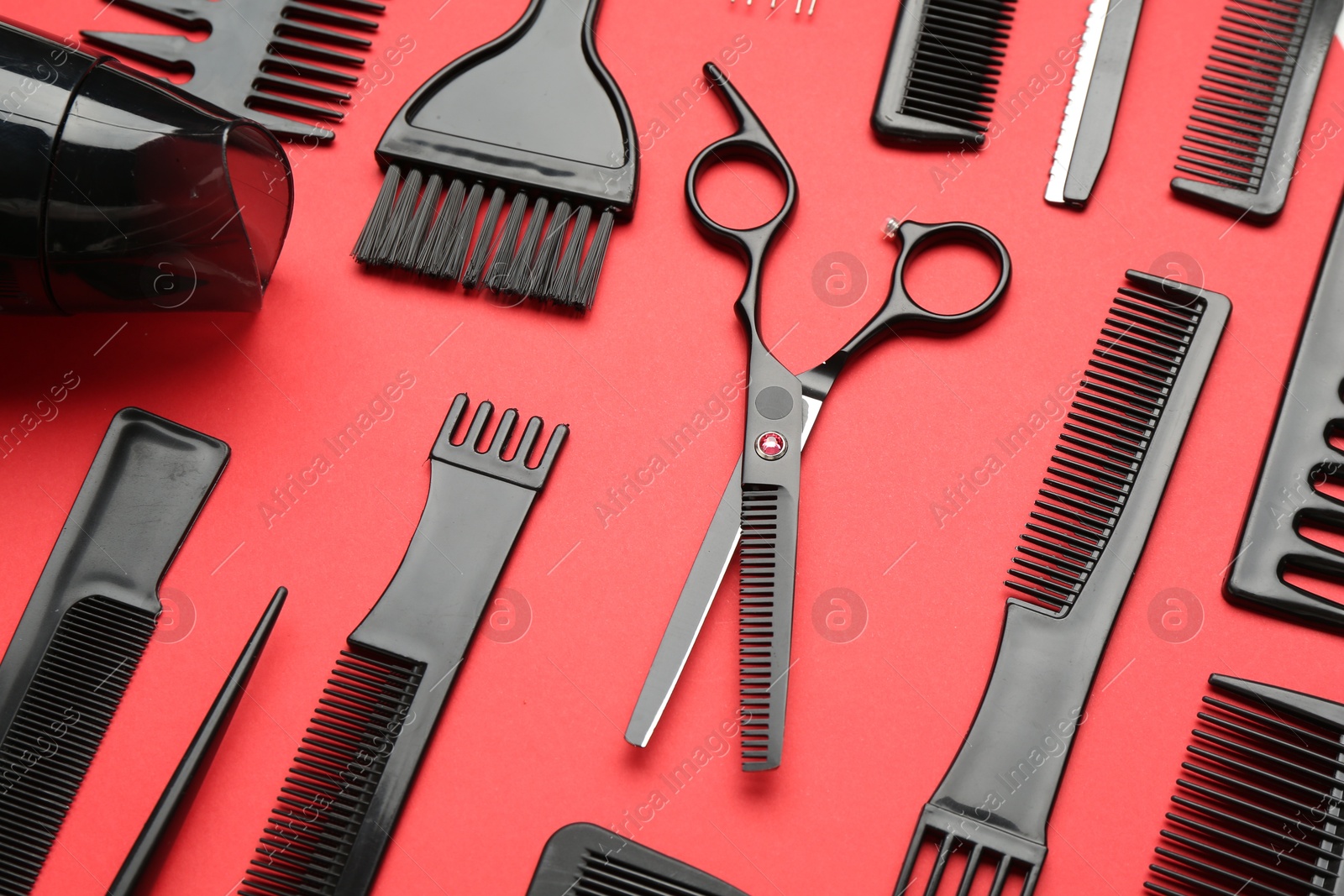 Photo of Different hairdresser's tools on red background, flat lay