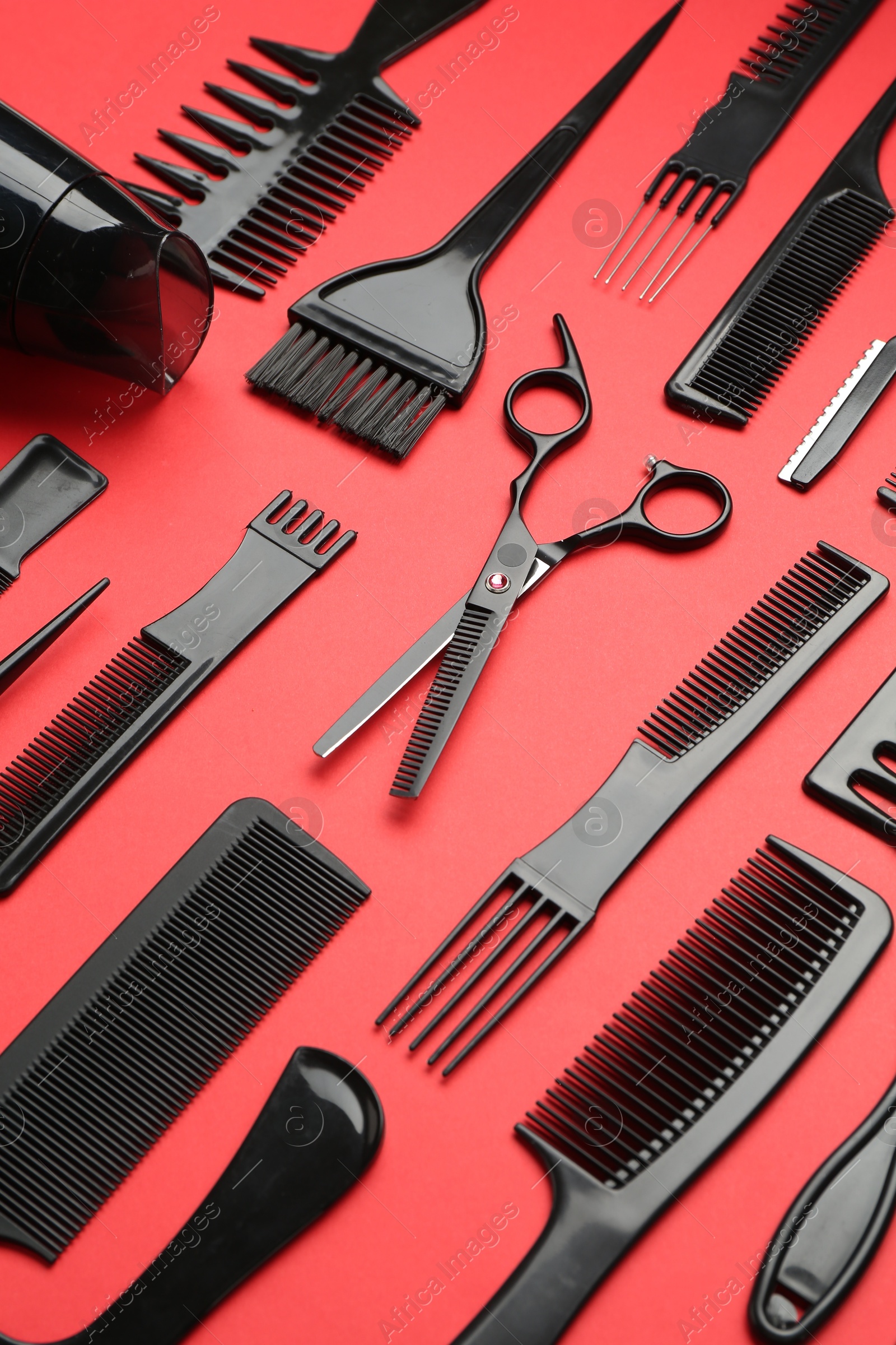 Photo of Different hairdresser's tools on red background, above view