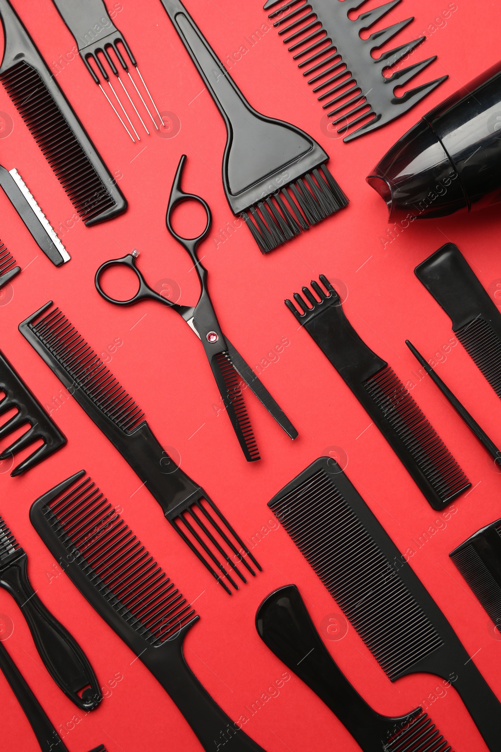 Photo of Different hairdresser's tools on red background, flat lay