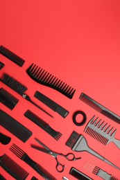 Photo of Different hairdresser's tools on red background, flat lay. Space for text