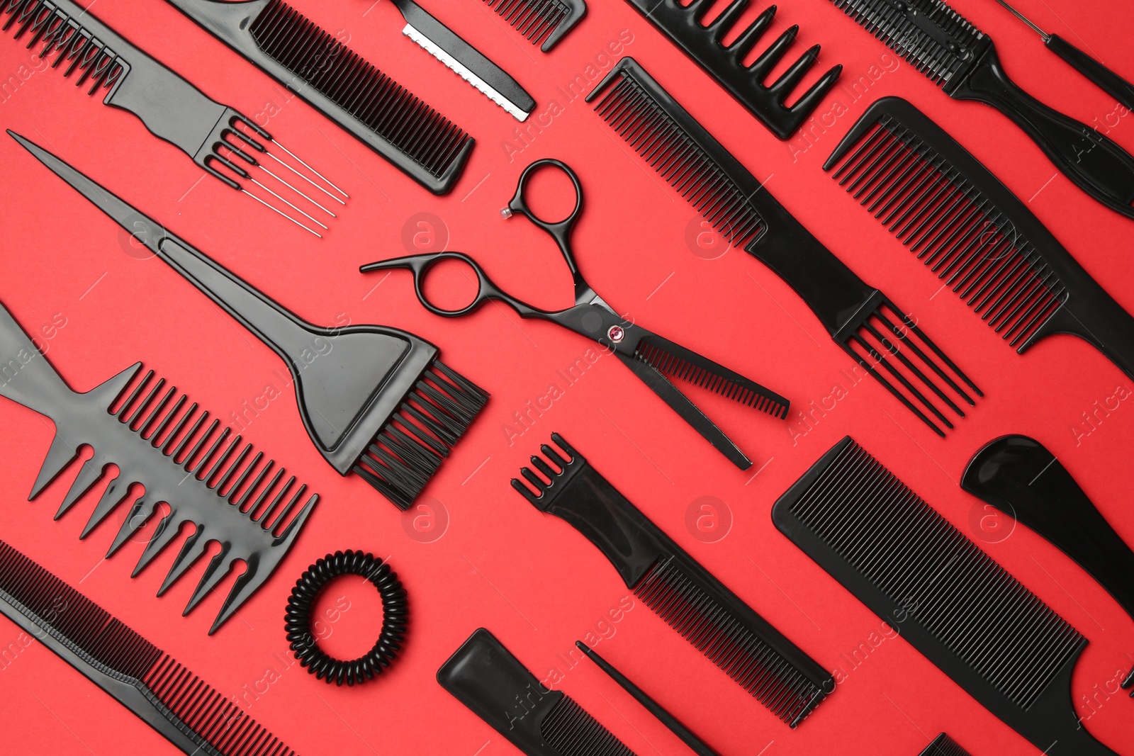 Photo of Different hairdresser's tools on red background, flat lay