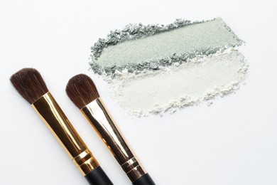 Photo of Eyeshadow smudges and brushes on white background, flat lay