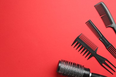 Photo of Different hairdresser's tools on red background, flat lay. Space for text