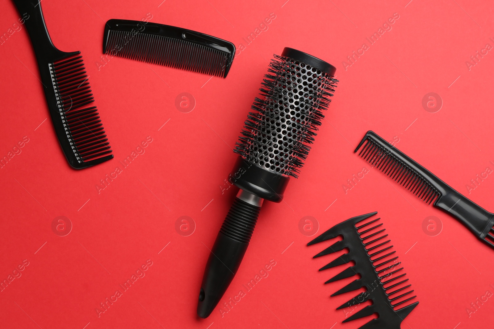 Photo of Different hairdresser's tools on red background, flat lay