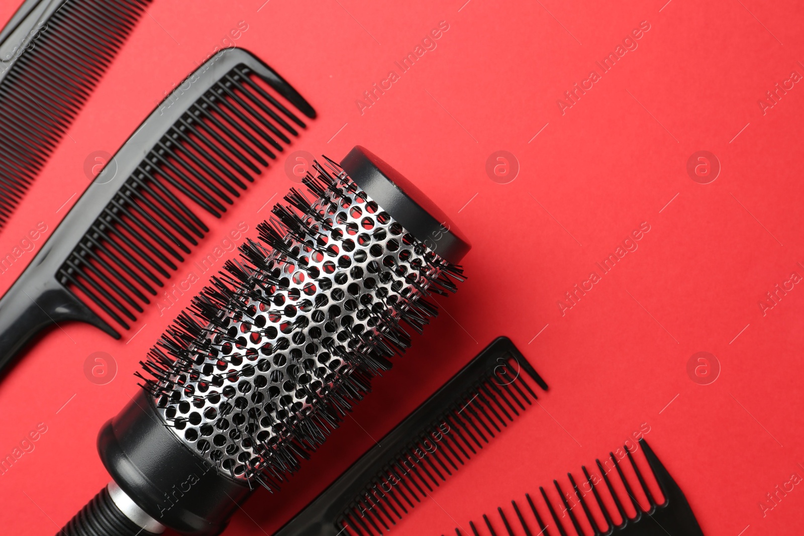 Photo of Different hairdresser's tools on red background, flat lay. Space for text