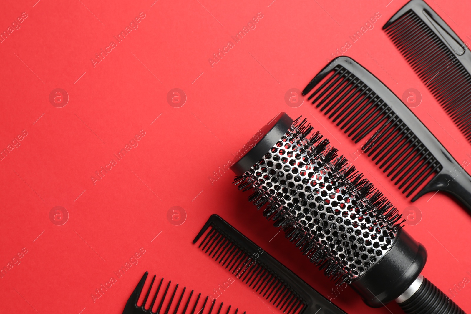 Photo of Different hairdresser's tools on red background, flat lay. Space for text
