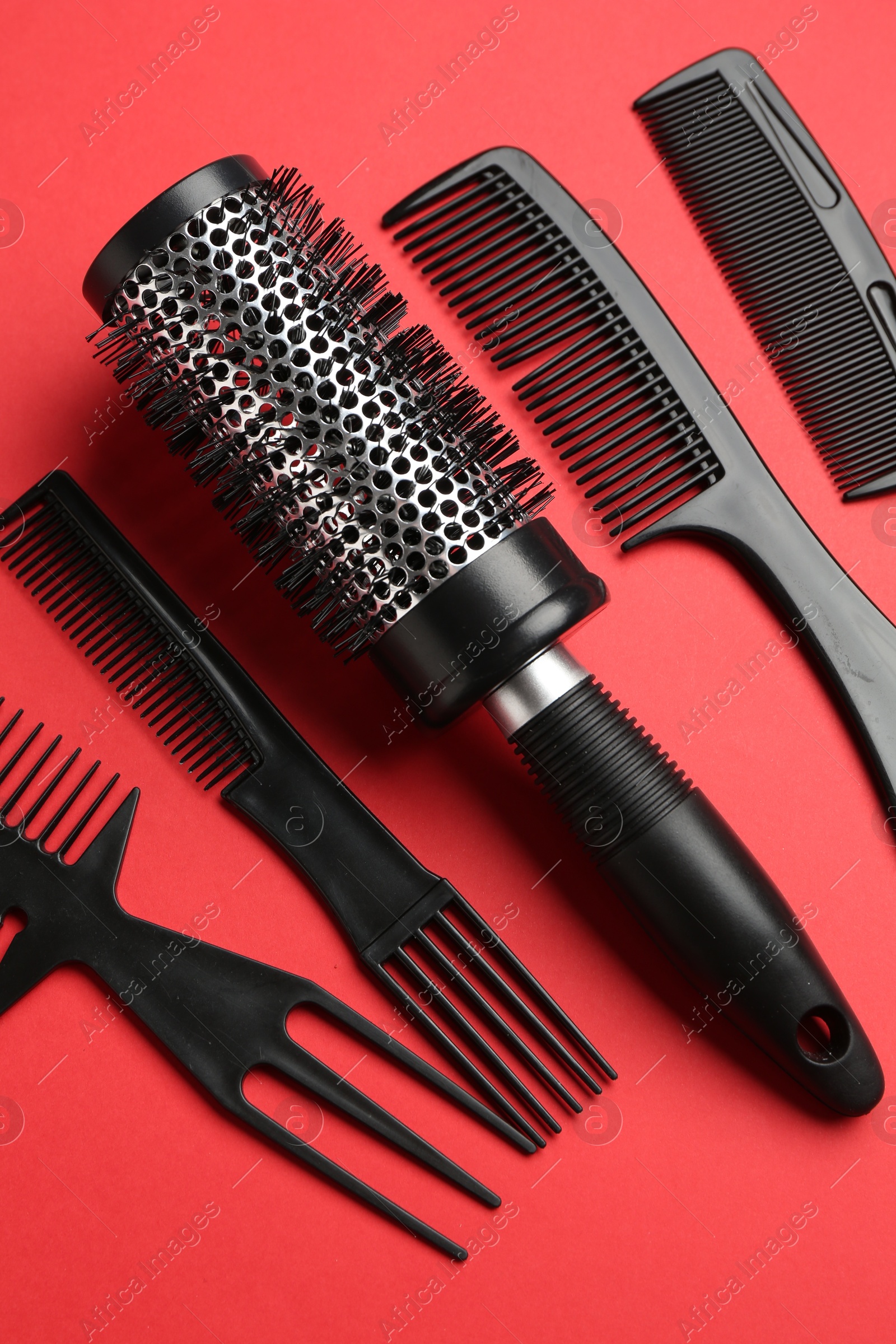 Photo of Different hairdresser's tools on red background, flat lay