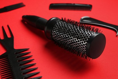 Photo of Different hairdresser's tools on red background, closeup