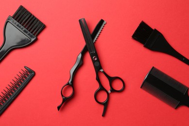 Photo of Different hairdresser's tools on red background, flat lay