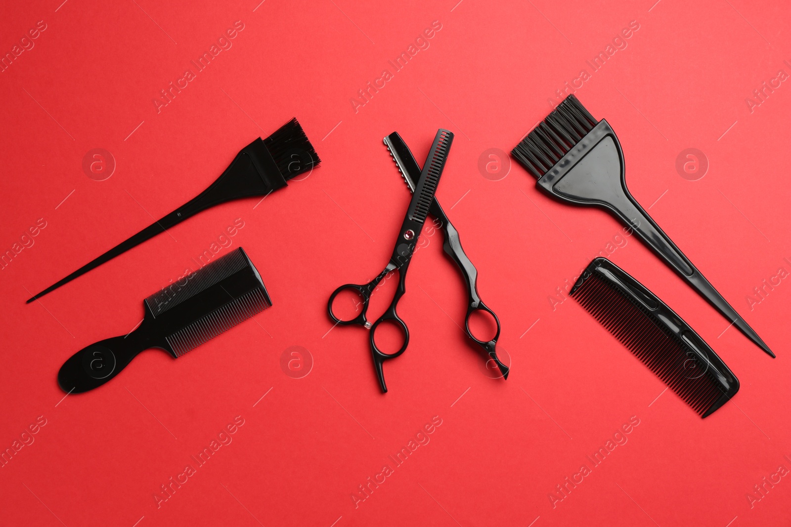 Photo of Different hairdresser's tools on red background, flat lay