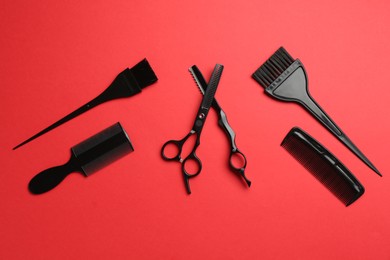Photo of Different hairdresser's tools on red background, flat lay