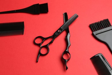 Photo of Different hairdresser's tools on red background, above view