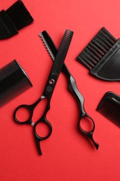 Photo of Different hairdresser's tools on red background, flat lay