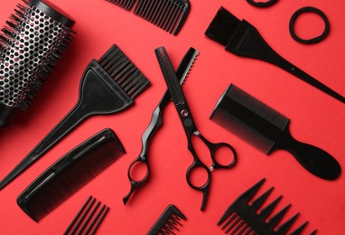 Photo of Different hairdresser's tools on red background, flat lay