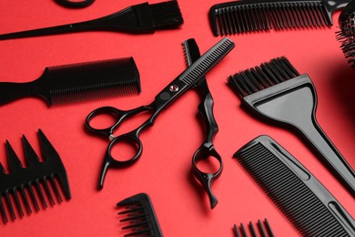 Photo of Different hairdresser's tools on red background, closeup