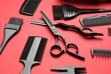 Photo of Different hairdresser's tools on red background, closeup