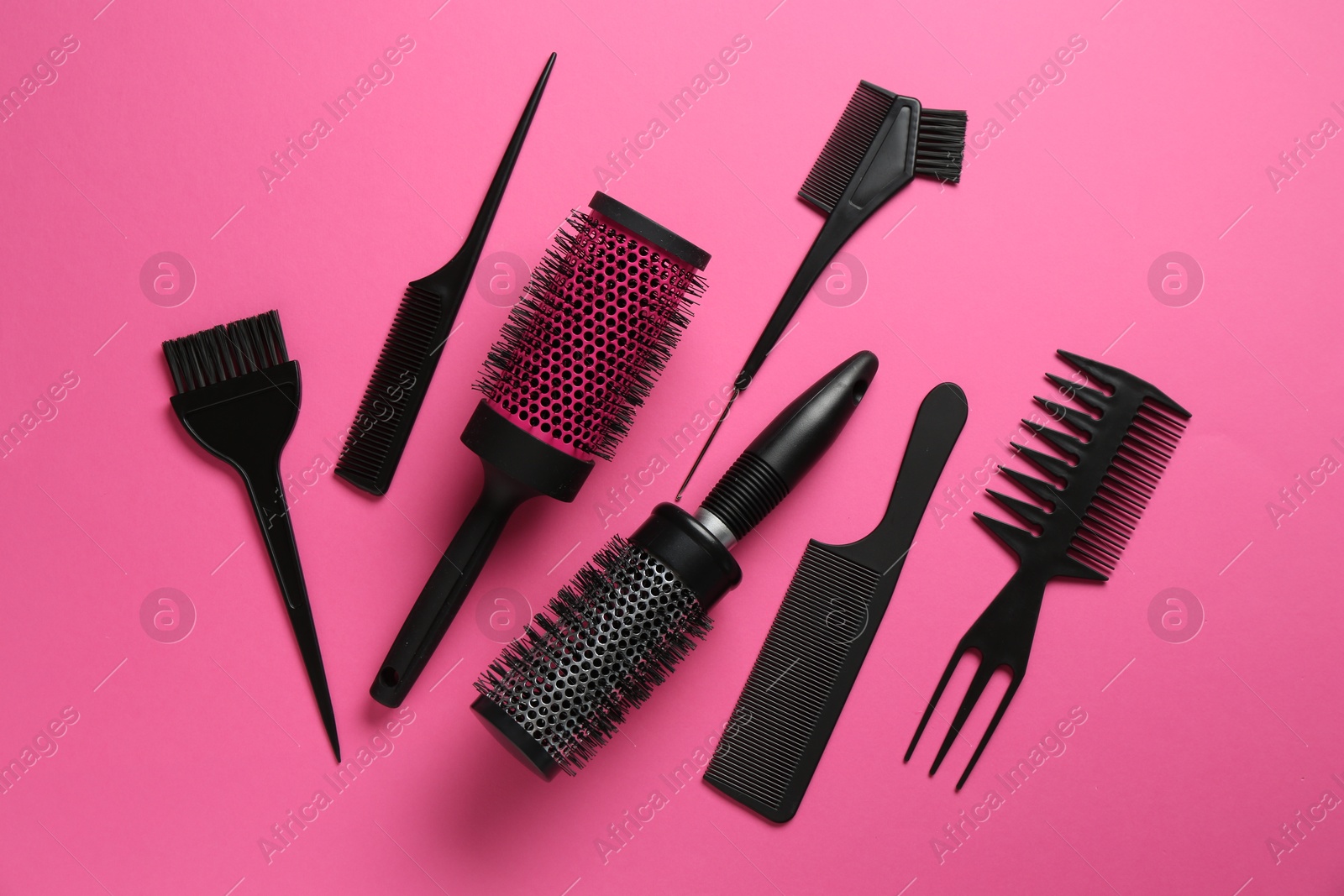 Photo of Different hairdresser's tools on pink background, flat lay