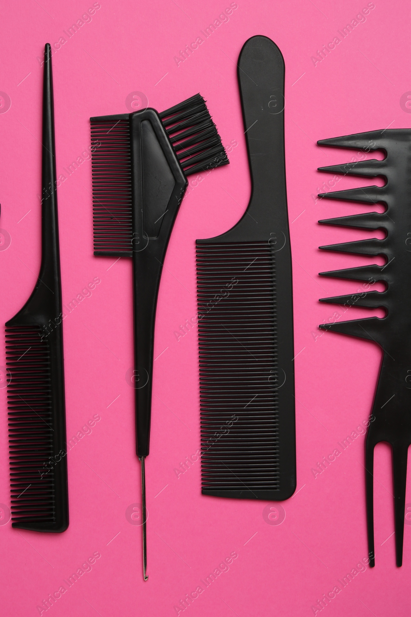 Photo of Different hairdresser's tools on pink background, flat lay