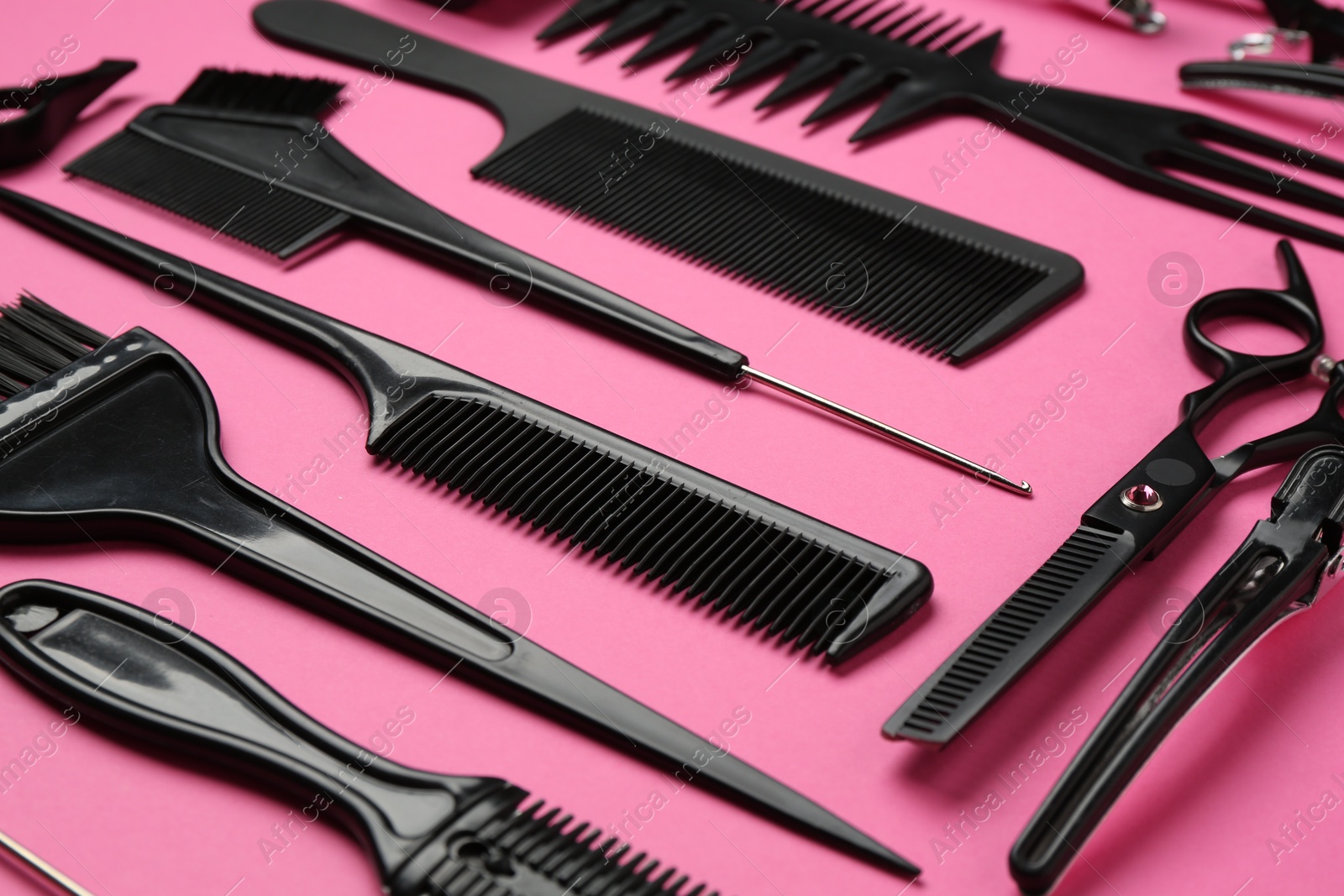 Photo of Different hairdresser's tools on pink background, closeup