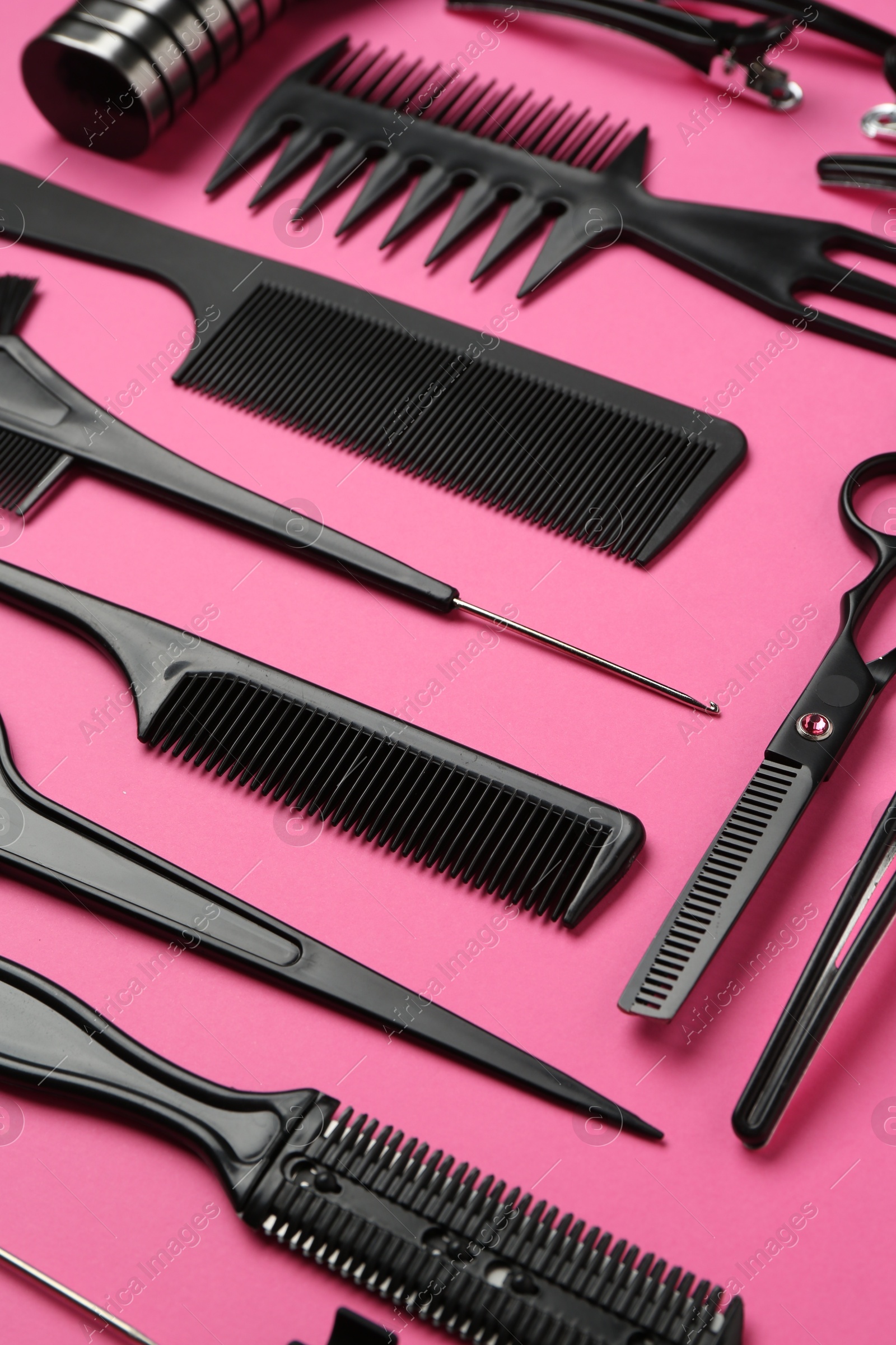 Photo of Different hairdresser's tools on pink background, closeup