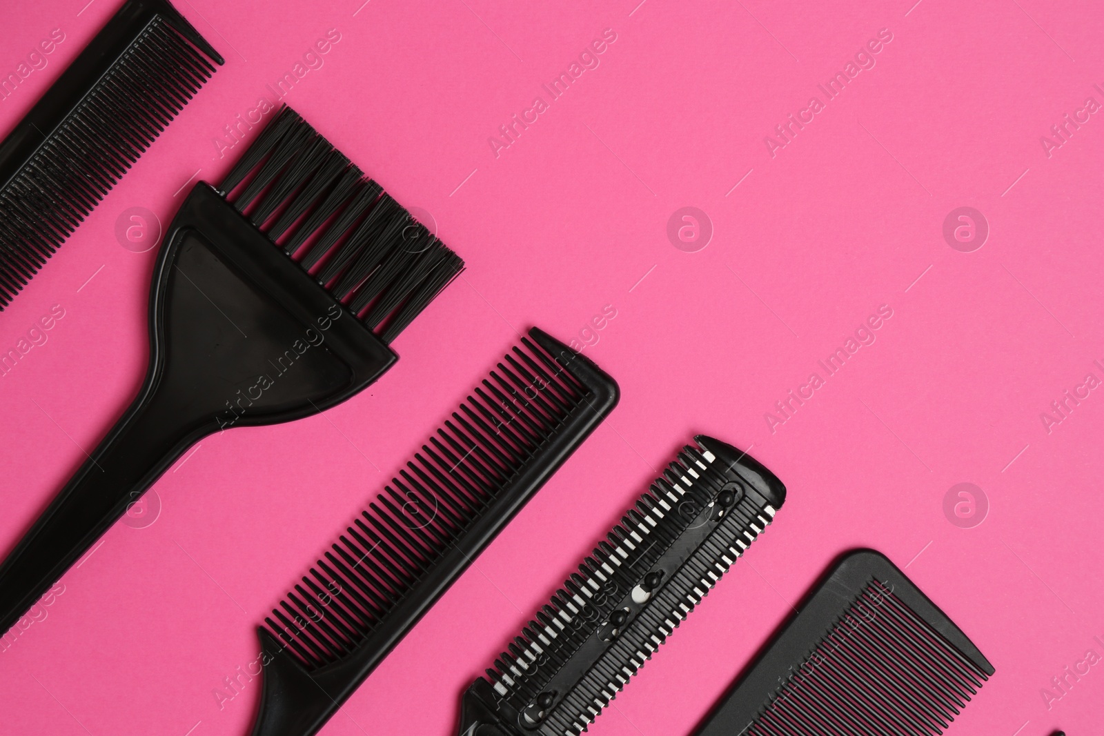 Photo of Different hairdresser's tools on pink background, flat lay. Space for text