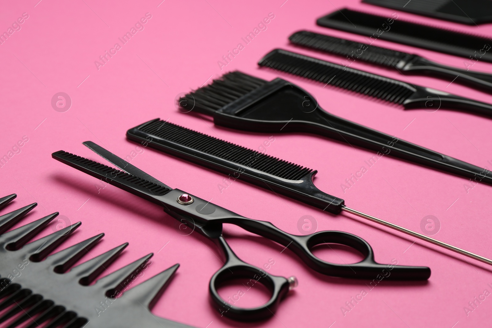 Photo of Different hairdresser's tools on pink background, closeup
