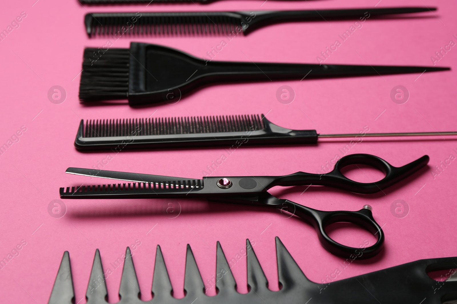 Photo of Different hairdresser's tools on pink background, closeup