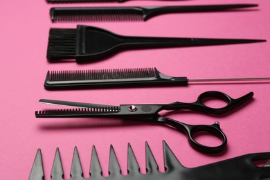 Photo of Different hairdresser's tools on pink background, closeup