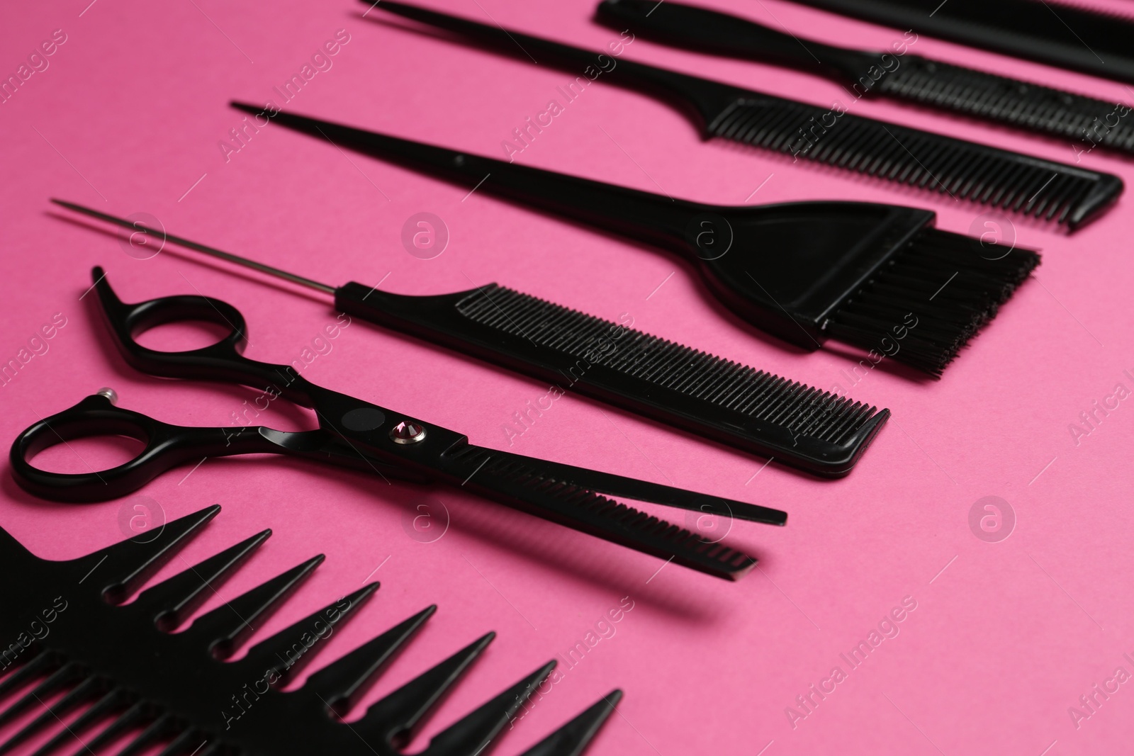 Photo of Different hairdresser's tools on pink background, closeup