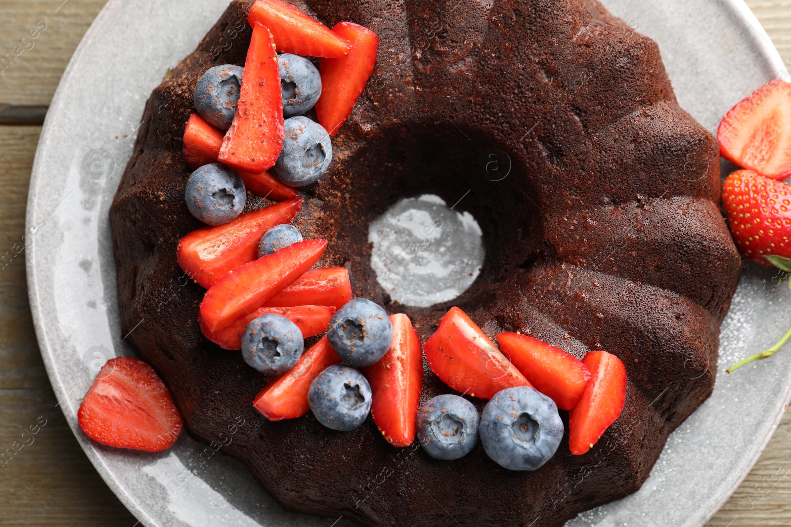 Tasty chocolate bundt cake with berries on wooden table, top view Photo of Tasty chocolate bundt cake with berries on wooden table, top view