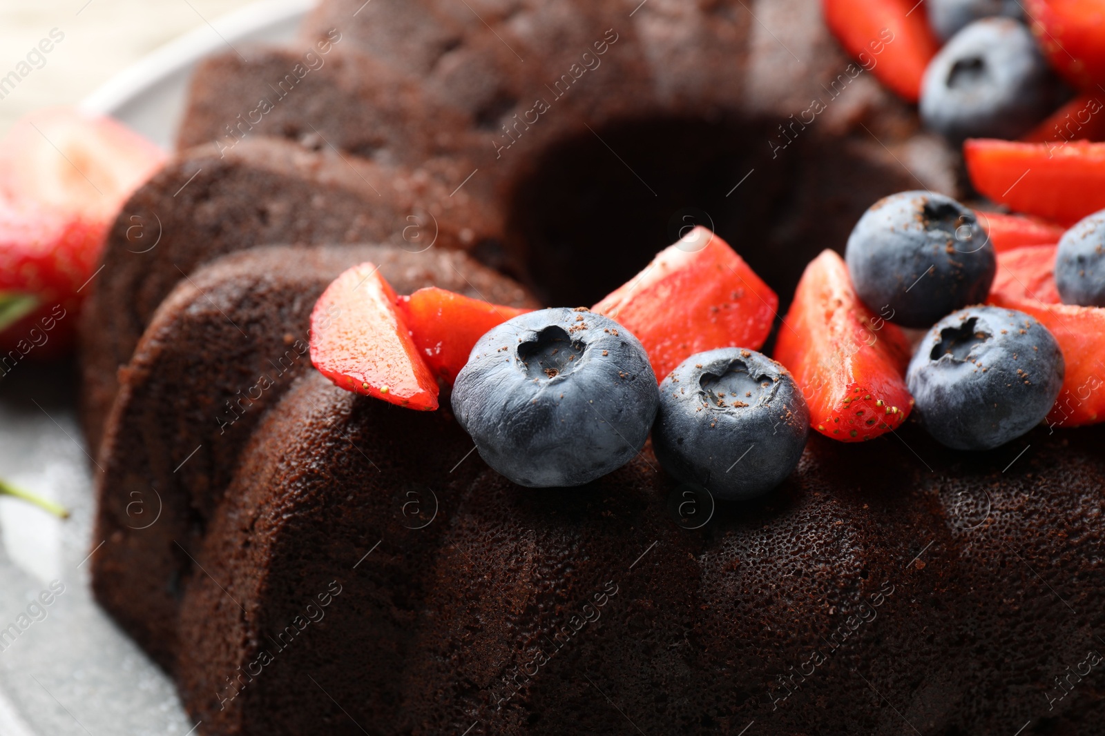 Tasty chocolate bundt cake with berries on table, closeup Photo of Tasty chocolate bundt cake with berries on table, closeup
