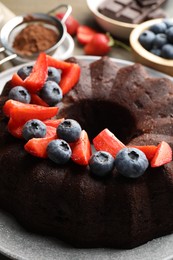 Photo of Tasty chocolate bundt cake with berries on table, closeup