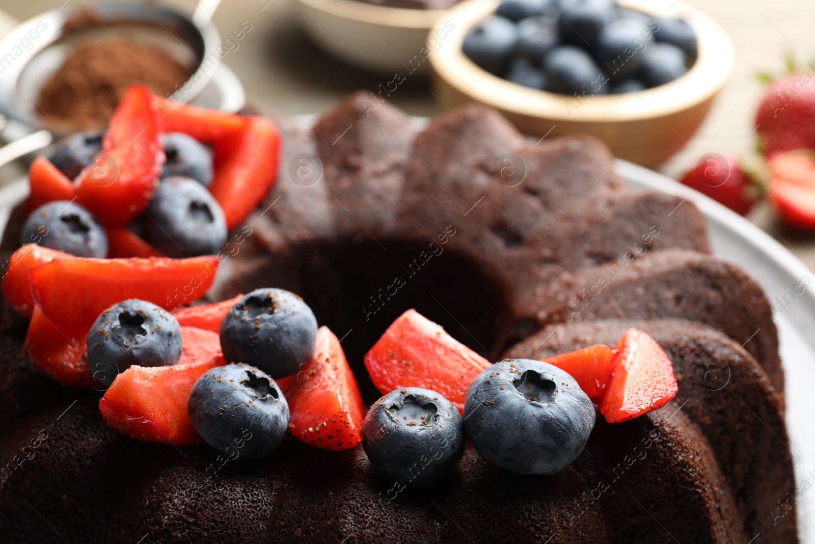 Tasty chocolate bundt cake with berries on table, closeup Photo of Tasty chocolate bundt cake with berries on table, closeup