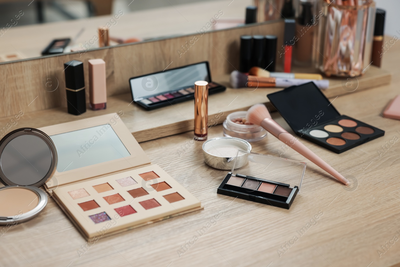 Different makeup products and brush on vanity indoors Photo of Different makeup products and brush on vanity indoors