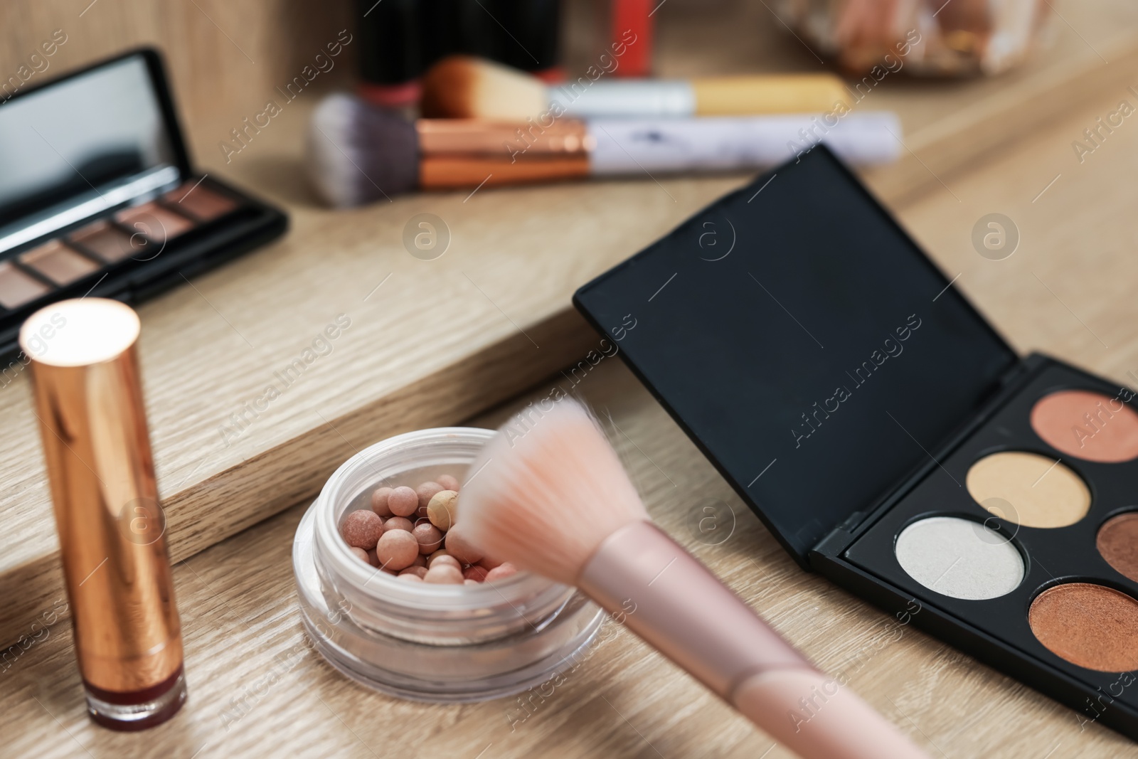 Different makeup products and brush on vanity indoors, closeup Photo of Different makeup products and brush on vanity indoors, closeup