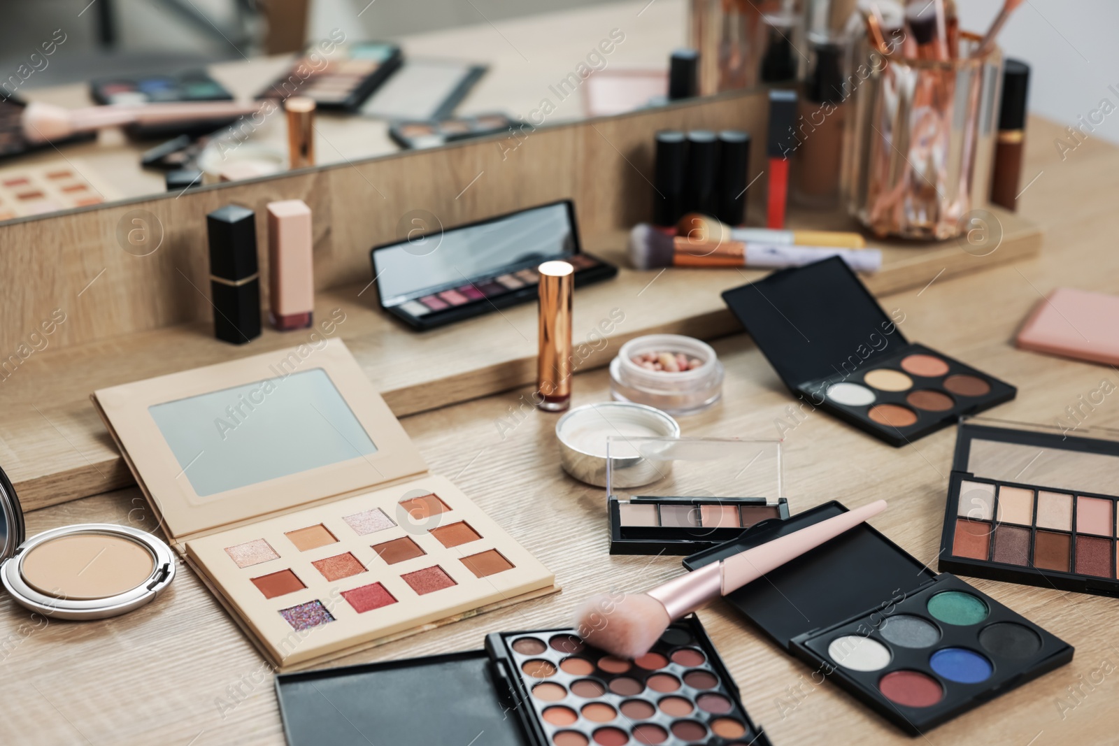 Different makeup products and brush on vanity indoors Photo of Different makeup products and brush on vanity indoors
