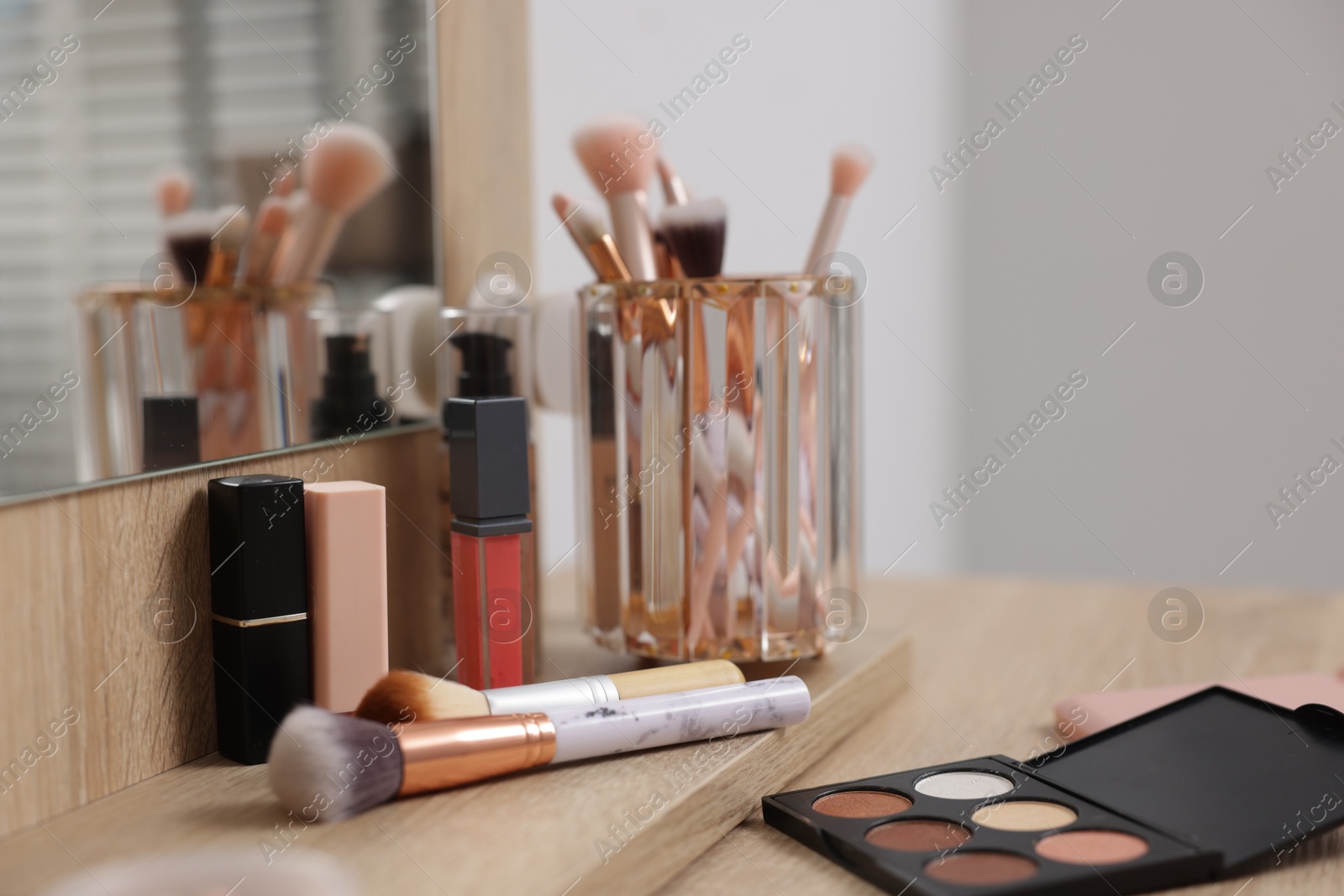 Different makeup products and brushes on vanity indoors, closeup Photo of Different makeup products and brushes on vanity indoors, closeup