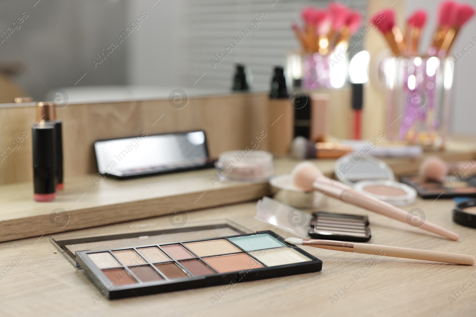 Different makeup products and brushes on vanity indoors Photo of Different makeup products and brushes on vanity indoors
