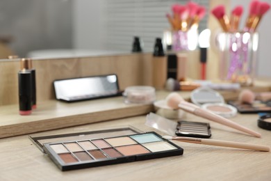 Photo of Different makeup products and brushes on vanity indoors