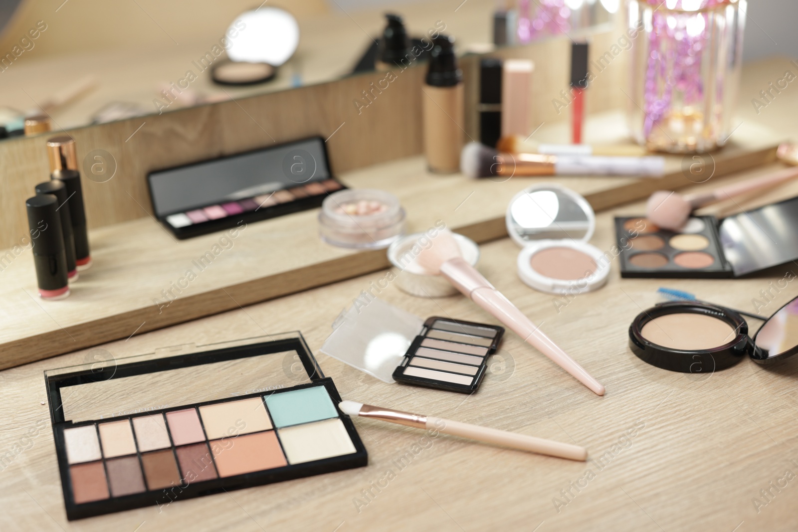 Different makeup products and brushes on vanity indoors Photo of Different makeup products and brushes on vanity indoors