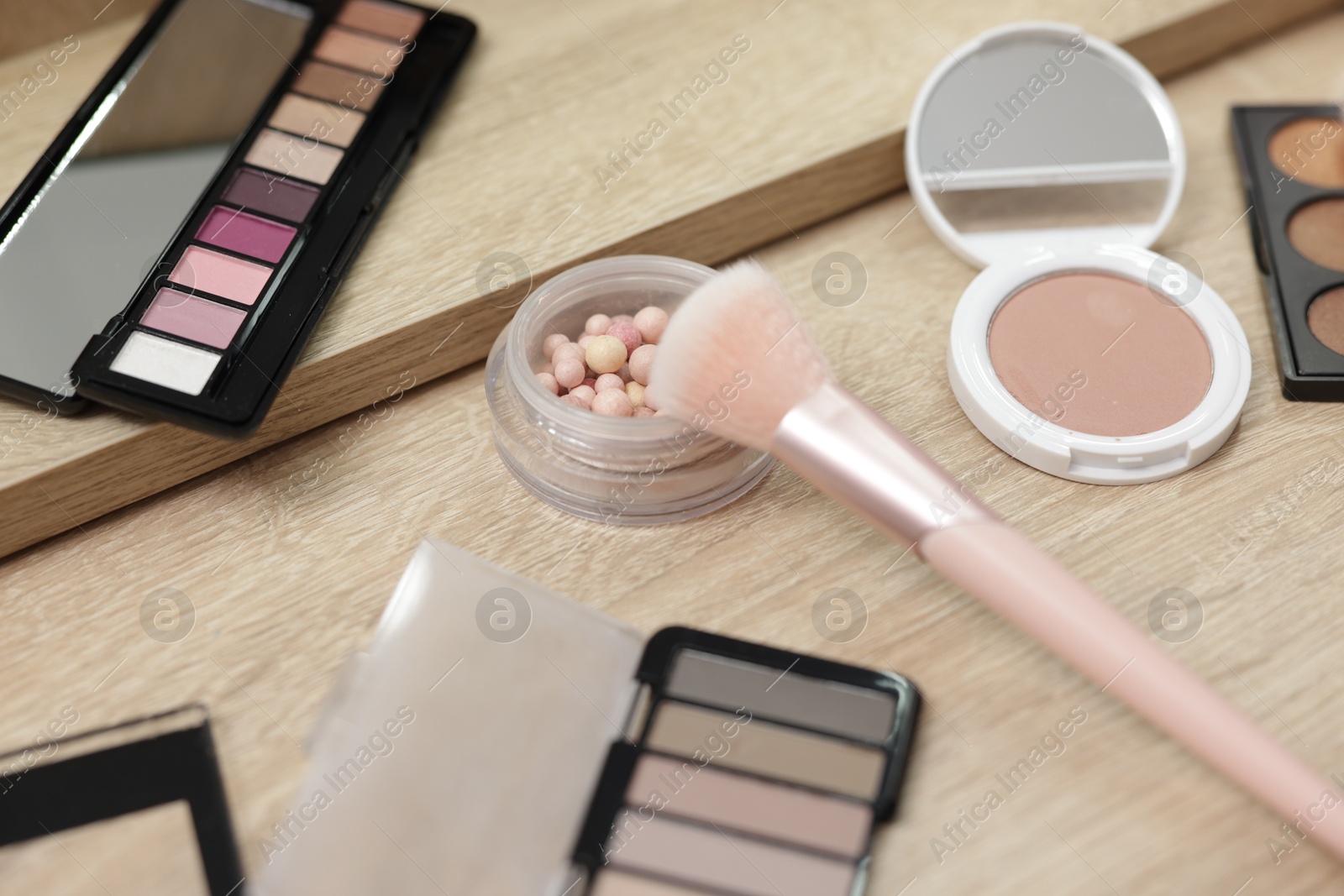 Different makeup products and brush on vanity indoors, closeup Photo of Different makeup products and brush on vanity indoors, closeup