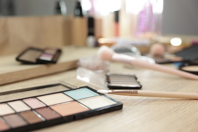 Photo of Different makeup products and brushes on vanity indoors, closeup