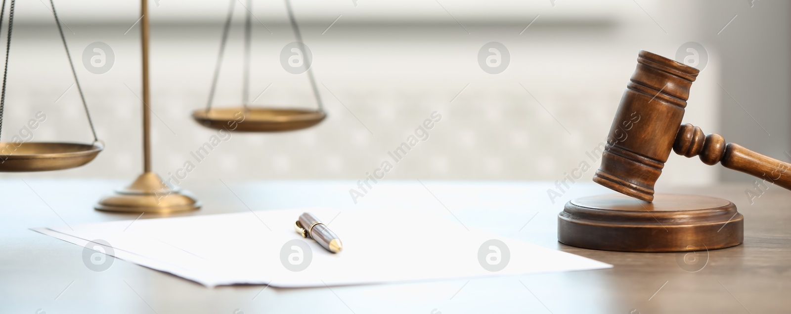 Photo of Papers, judge's gavel and scales on wooden table in office, closeup