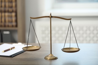 Photo of Judge's workplace with scales and clipboard on wooden table in office, closeup