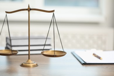 Photo of Judge's workplace with scales, books and clipboard on wooden table in office, closeup
