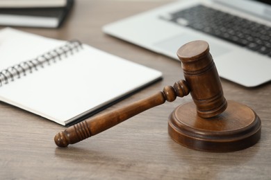 Photo of Laptop, judge's gavel and notebook on wooden table in office, closeup