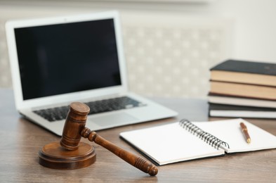 Photo of Laptop, judge's gavel and notebook on wooden table in office